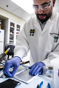 Ahmet Emrehan Emre, a biomedical engineering PhD candidate, sandwiches a thin sheet of a cartilage-like material between a layer of zinc on top and a layer of manganese oxide underneath to form a battery. Image credit: Evan Dougherty/Michigan Engineering