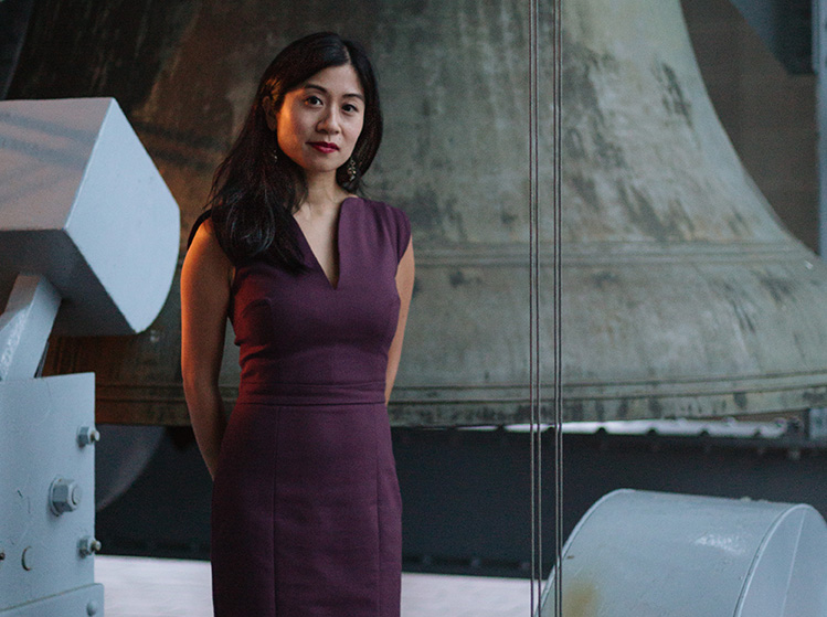 Photo of Tiffany Ng in front of a carillon bell