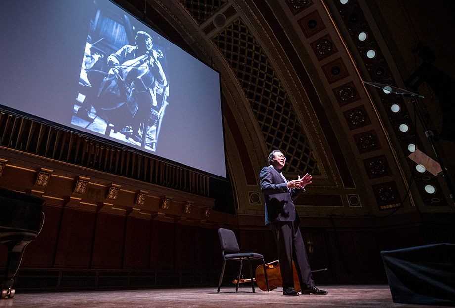 Photo of Yo-Yo Ma in front of an image of him as a young man