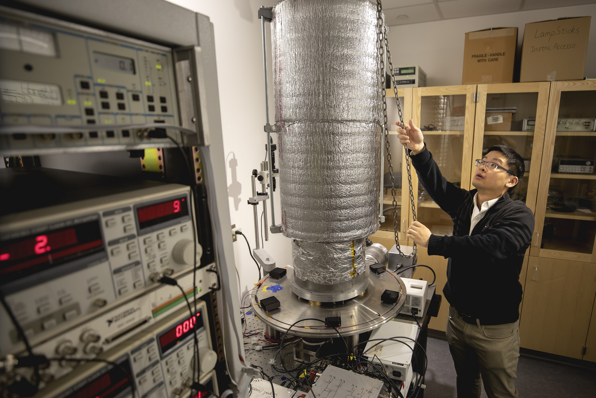 Linxiao Zhu shows the experimental platform that housed the calorimeter and photodiode. This system can damp vibrations from the room and building, steadily holding the two nanoscale objects 55 nanometers (0.000055 millimeters) apart. Image credit: Joseph Xu