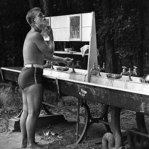 Camper shaves at outdoor sink.