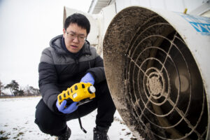 Tian Xia monitors the methane levels coming out of a pig holding pen before setting up a lab-scale non-thermal plasma device at the Barton Farms family pig farm in Homer, MI. Image credit: Robert Coelius/Michigan Engineering