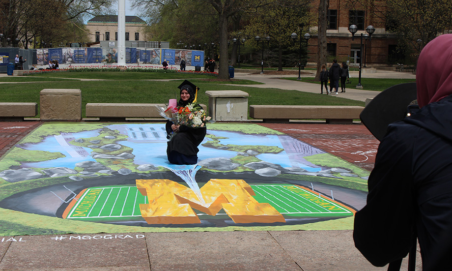 Photo of LSA graduate Abrar Habib at the “Michigan Reflections" 3-D display on the Diag.