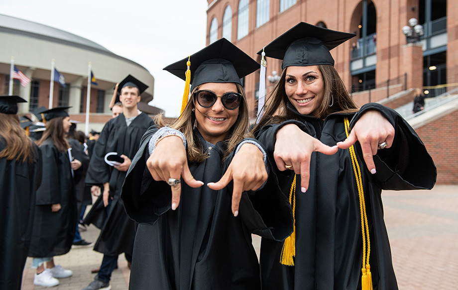 Photo of graduates making an "M" sign with their hands