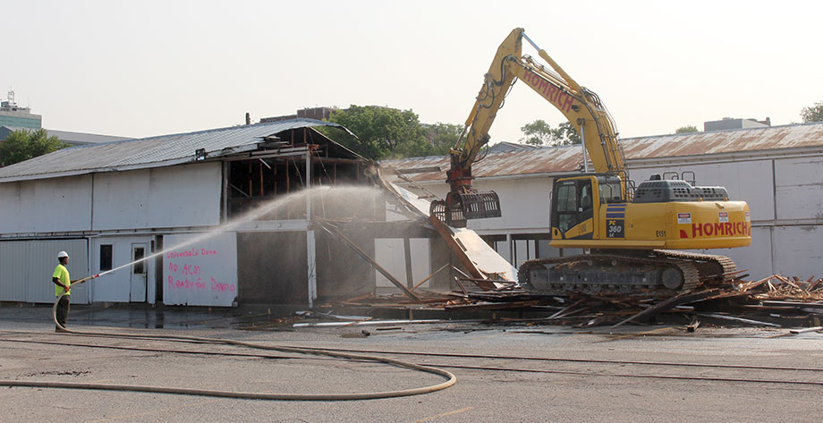 Photo of workers from Homrich demolishing university property on South Fifth Avenue.