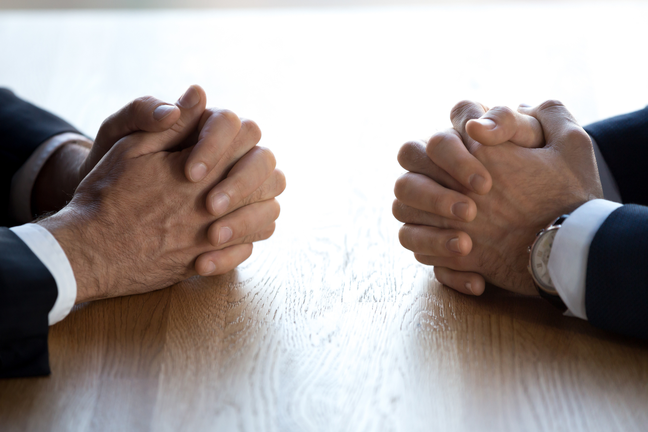 Clasped hands of two business men negotiators opponents opposite on table as politicians dialogue debate, applicant hr job interview, negotiating competitors, rivals confrontation challenge concept. iStock