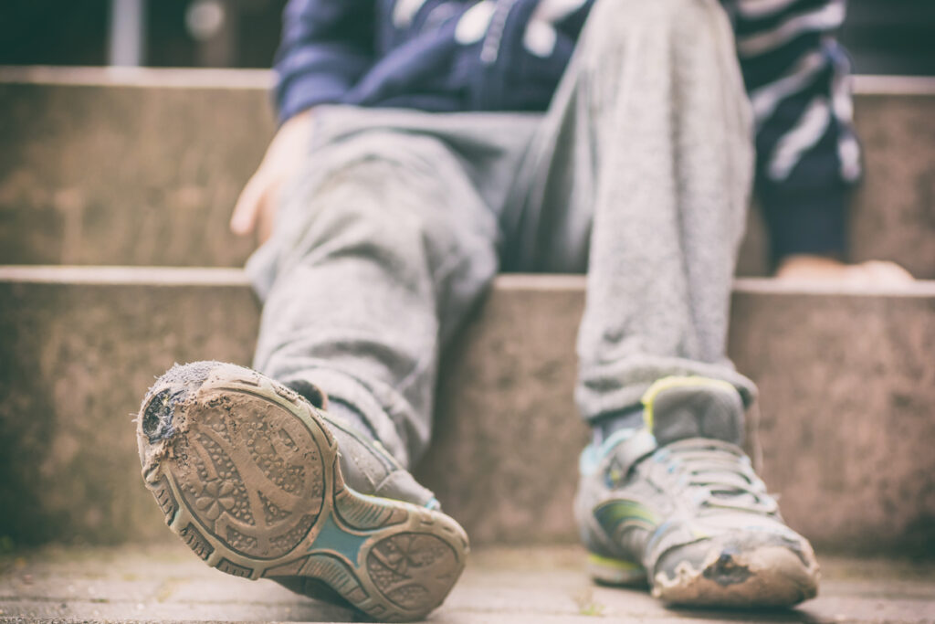 Old broken shoes of a person sitting outdoors on steps. Image credit: iStock