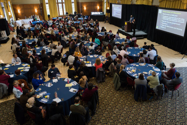 Photo of about 200 people gathered in the Michigan League Ballroom for the DEI progress report.