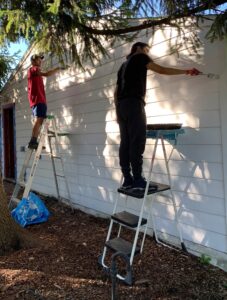 U-M students Rahul Ribiero, left, and Vincent Sposato help paint at Growing Hope Urban Farm in Ypsilanti through the Michigan Community Scholars Program. The program, which is celebrating its 20th anniversary, offers students meaningful civic engagement and intercultural understanding. (Photo by Emily Welch)