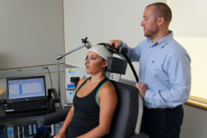 Adam Lepley, assistant professor of kinesiology, prepares a model subject for transcranial magnetic stimulation at the Phillips Communication Sciences Building, University of Connecticut, on July 17, 2017. Image credit: Peter Morenus