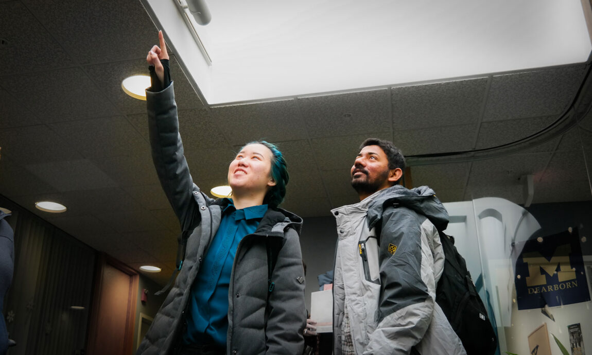 UM-Dearborn College of Engineering and Computer Science graduate students Christine Li (left) and Viraj Tulaskar inspect a skylight in the Administration Building as part of the DTE Energy E-Challenge Competition.