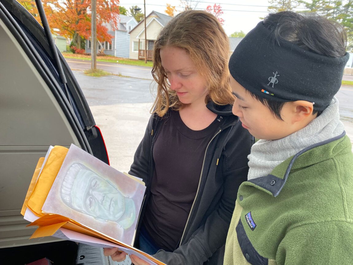 U-M graduate students Megan Wilson and Jessie Zhou look over artwork.