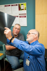 Howard Winchel (left) and Dr. Philip Baty discuss Winchel's X-ray. Image credit: Eric Bronson, Michigan Photography