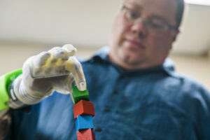 Joe Hamilton, a participant in the U-M RPNI study, naturally uses his mind to control a DEKA prosthetic hand to pick up a small block. Image credit: Evan Dougherty, Michigan Engineering