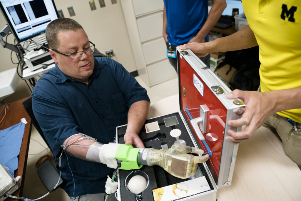 Joe Hamilton, a participant in the University of Michigan RPNI study, naturally uses his mind to control a DEKA prosthetic hand to pinch a small zipper on a hand development testing platform. Image credit: Evan Dougherty, Michigan Engineering