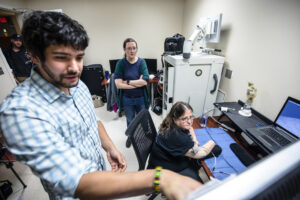 During a critical testing session for the University of Michigan RPNI study, Alex Vaskov, robotics Ph.D. candidate, Cindy Chestek, associate professor of biomedical engineering, and Karen Sussex, study participant, examine parameters for a prosthetic control exercise. Image credit: Evan Dougherty/University of Michigan Engineering