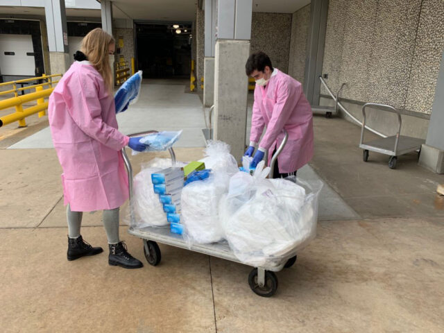 Medical students place donated supplies on a cart near the drive-through drop-off point, at Dock 90 of the North Campus Research Complex. 
