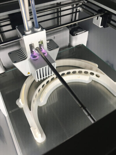 Photo of a 3-D printer at the Duderstadt Center’s 3D Lab produces a headband for the U-M/Prusa face shield.