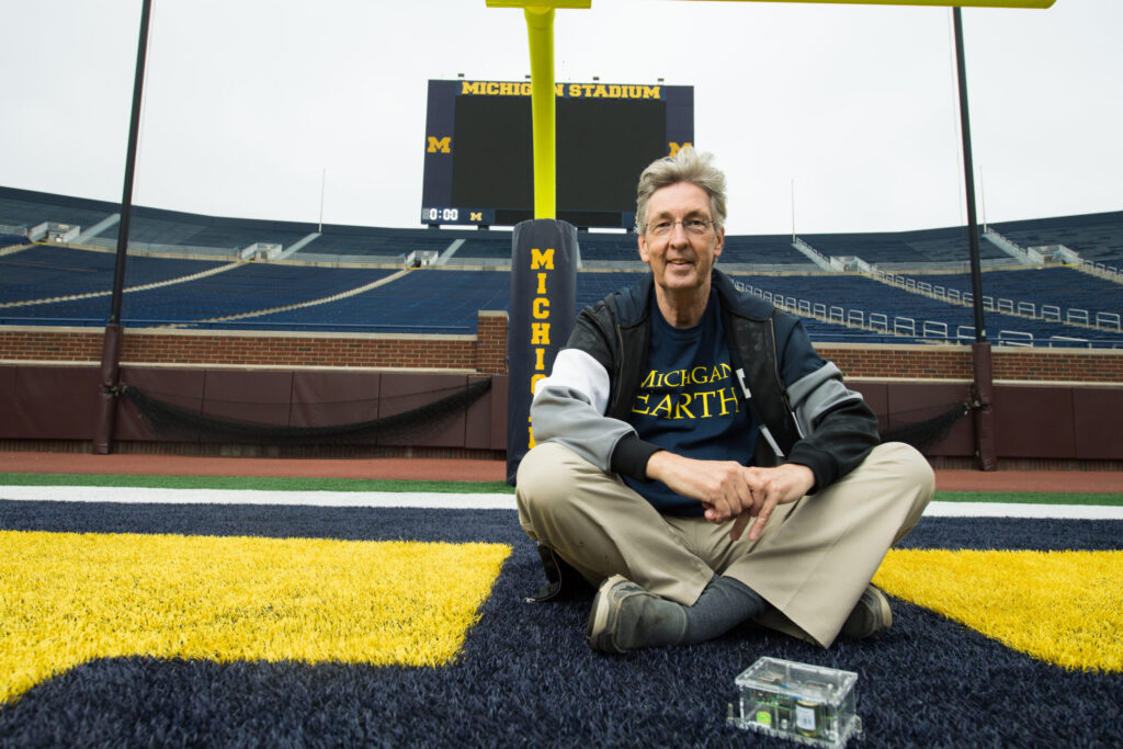 U-M geologist Ben van der Pluijm in Michigan Stadium in 2018 with a portable digital seismometer like the one used to measure crowd response during University of Michigan home football games. The stadium seismometer, and another one like it on the U-M Central Campus, are now being used to study the drop in ground-vibration noise during the COVID-19 pandemic. Image credit: Austin Thomason, Michigan Photography