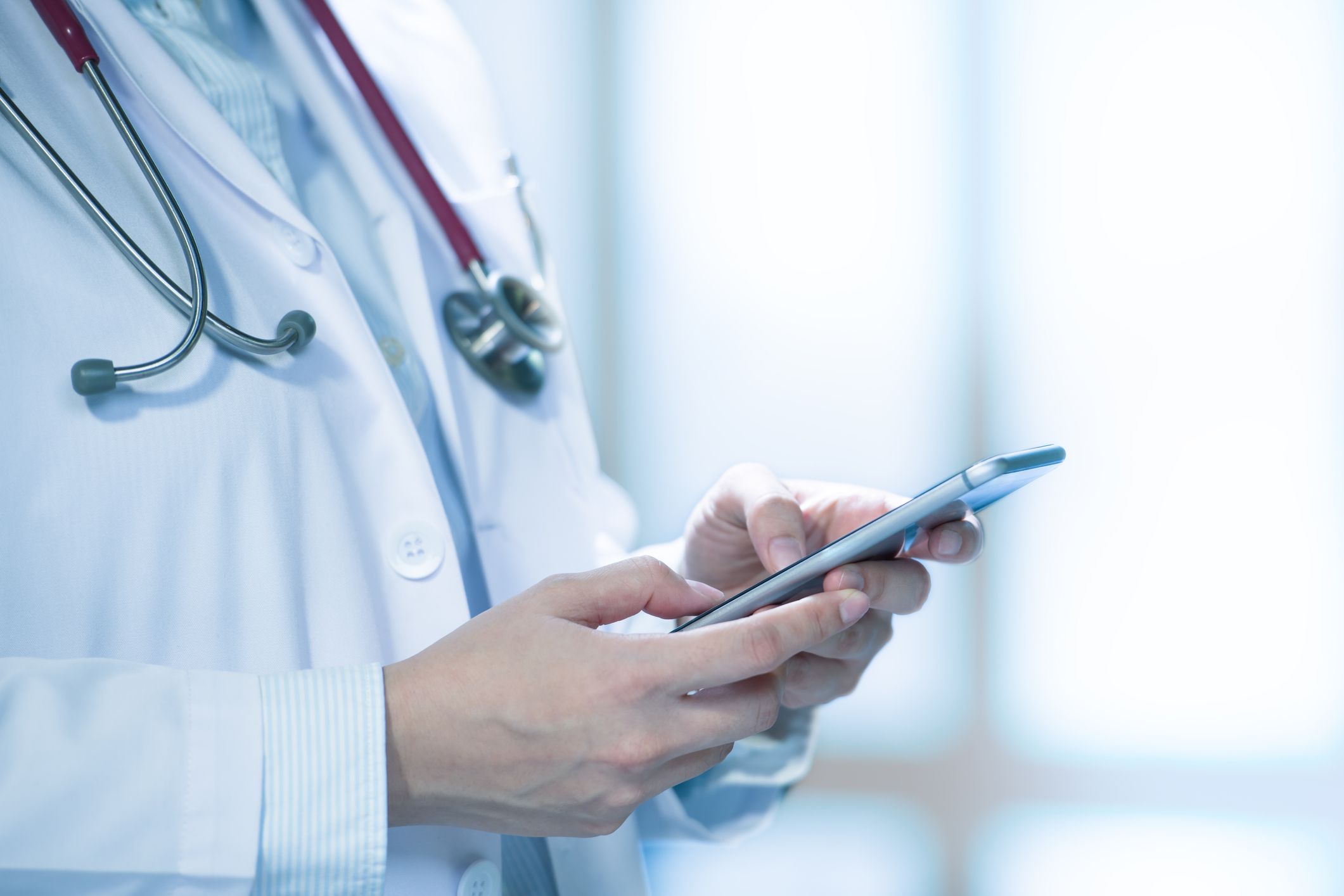 Medical doctor using smart phone for work in hospital. Image credit: iStock