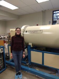 Student Bowen next to accelerator mass spectrometer.