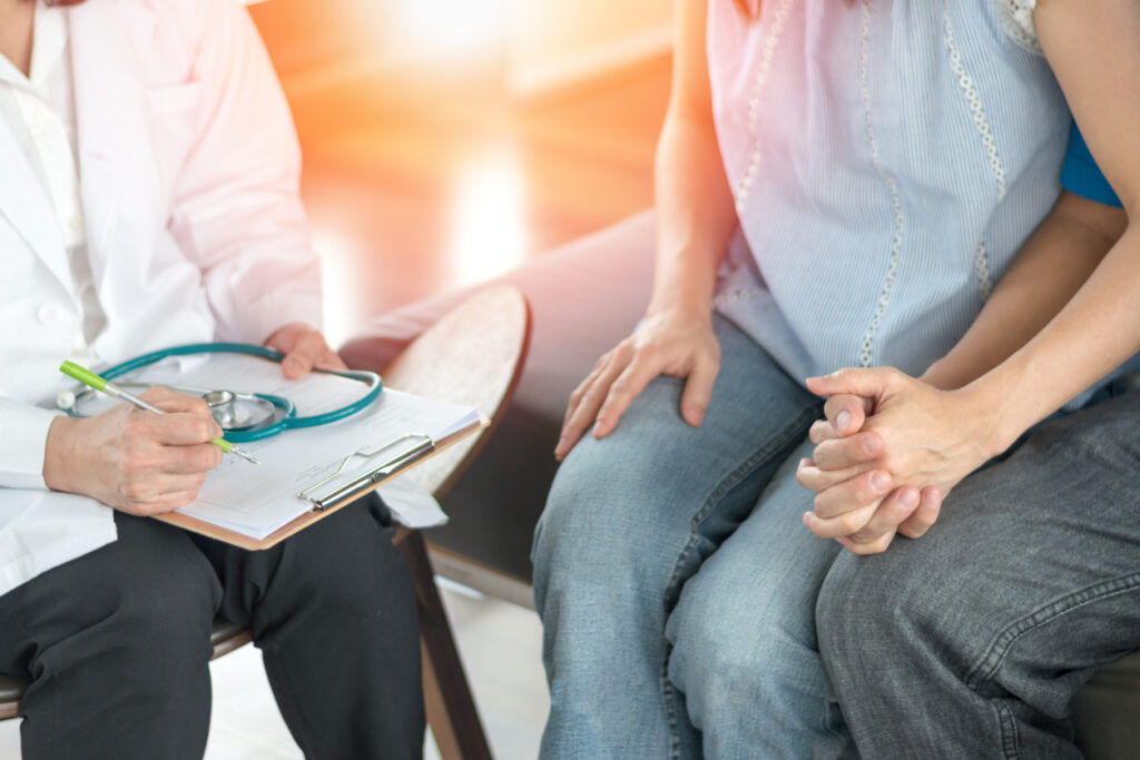 A couple holds hands while consulting with a doctor. Image credit: iStock