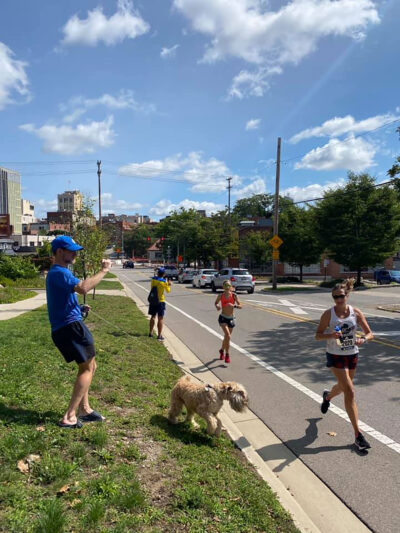 Colleen Stone approaches the finish line of the virtual Boston Marathon in Ann Arbor as her husband, Paul Livingstone, tries to capture a photo while also corralling their dog, Stevie.