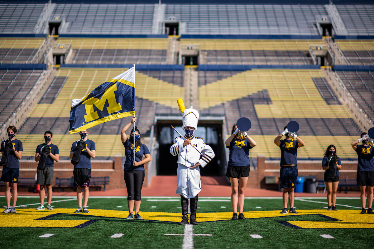 A small number of Michigan Marching Band members pose at the empty Michigan Stadium during a photoshoot. Image credit: Eric Bronson/Michigan Photography