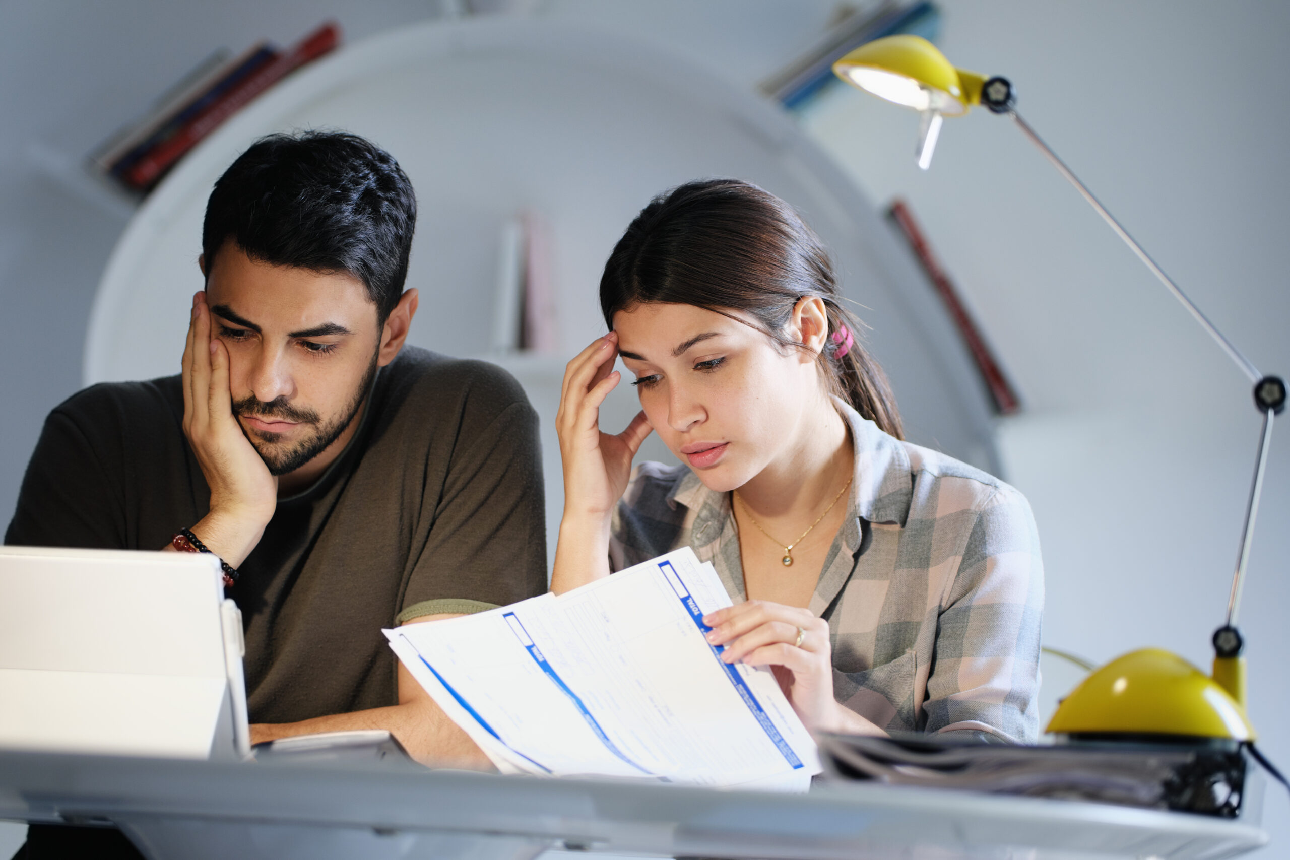 Young couple reviewing invoices and doing family business plan. Concept of money and economic problem for man and woman living together. Image credit: iStock