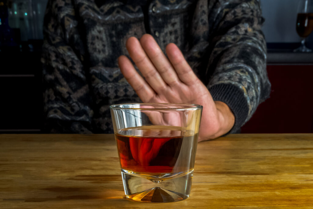 Male hand rejecting glass with alcoholic beverage. Image credit: iStock