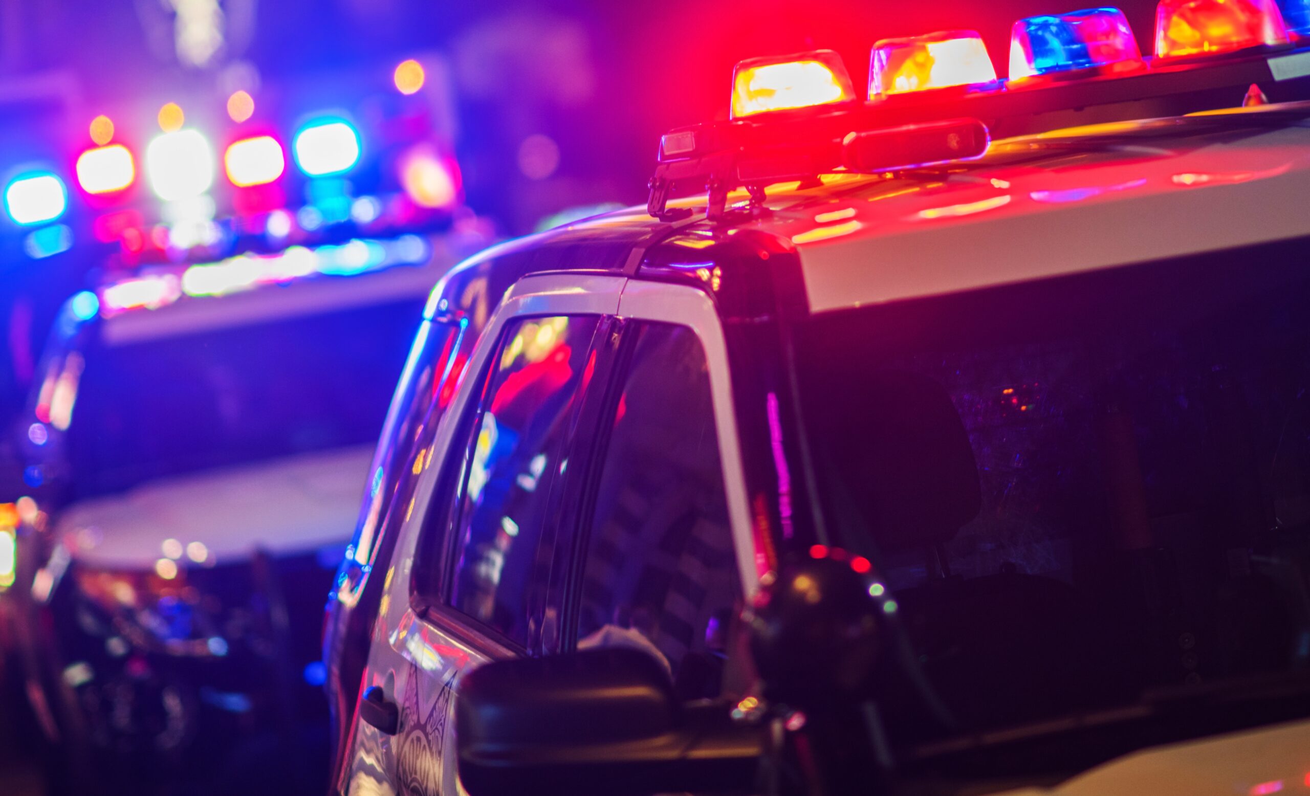 Night Time Police Violent Crime Intervention. Police Vehicles with Flashing Lights. Image credit: iStock