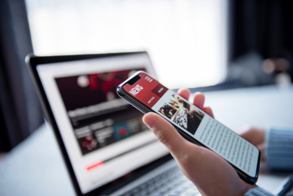 Online news on a smartphone and laptop. Image credit: iStock