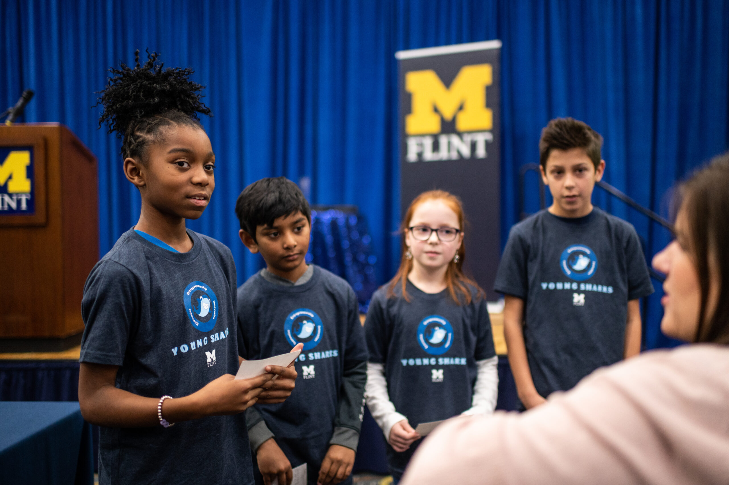 Students from Mason Elementary School of Grand Blanc Community Schools discuss their presentation strategy with their teacher during the presentation on 12/3/2019 at Riverfront Banquet Center on the UM-Flint campus. Image credit: Eric Bronson / Michigan Photography