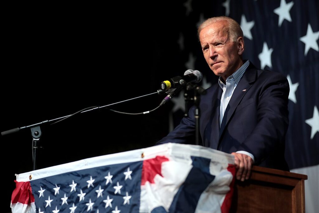 Joe Biden stands at a Flag-covered lectern. Image credit: Gage Skidmor via Flickr