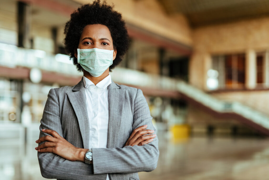 A Black woman wearing a suit and face mask. Image credit: iStock