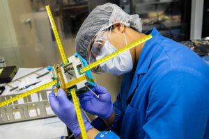 Mayukh Nath, Computer Engineering Undergraduate Student inspects the upper unit on the Mi-TEE (Miniature Tether Electrodynamics Experiment) cubesat inside a CLaSP laboratory on North Campus in Ann Arbor, MI. before it launches into Earth's Ionosphere. Image credit: Robert Coelius/ Michigan Engineering, Communications and Marketing