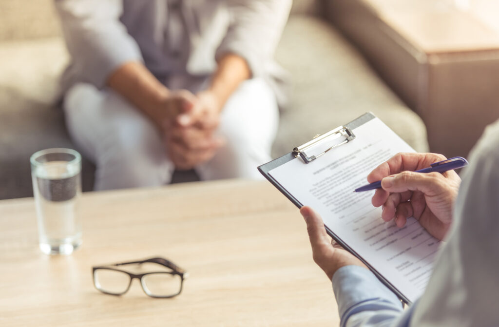 Cropped image of depressed man at the psychotherapist. Doctor is making notes while listening to his patient. Image credit: iStock