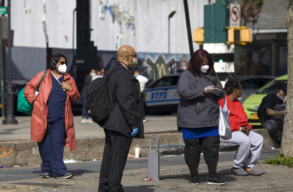 People wait for bus while wearing masks during COVID-19 Bronx NY. Image credit: eddtoro, iStock