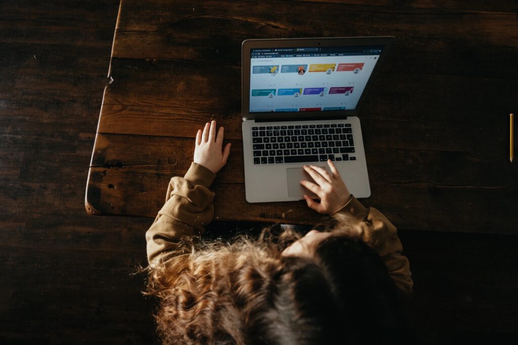 Overhead shot of a young person using a computer. Image credit: Annie Spratt, unsplash.com.