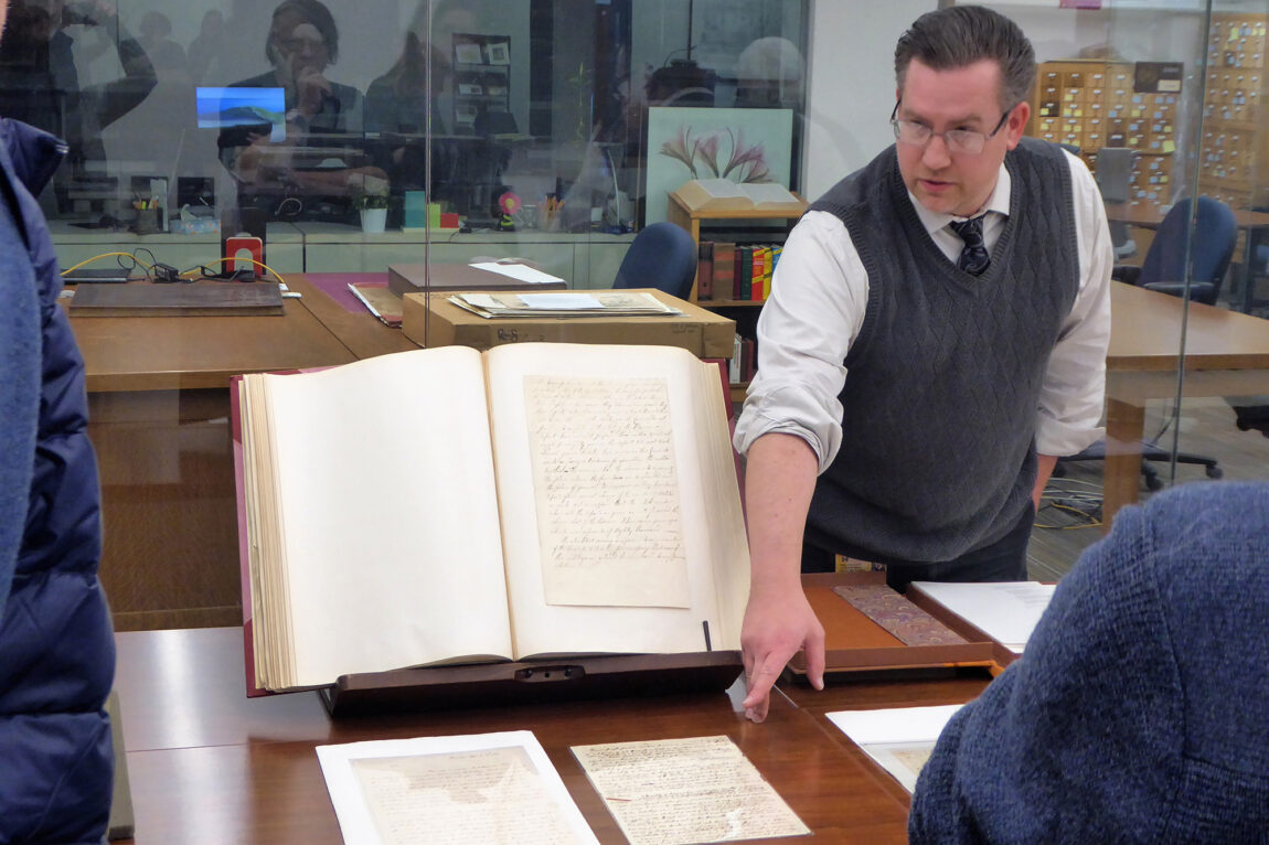 Photo of Cheney Schopieray, curator of manuscripts at the Clements Library, pointing to Thomas Gage’s original draft of his order to seize military stores at the town of Concord, west of Boston, April 18, 1775.
