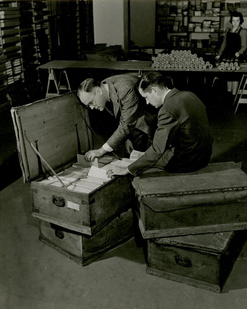 Photo of curators and staff members Lloyd Brown, Howard Peckham and Margaret Webber with four trunks of Thomas Gage papers in 1937.