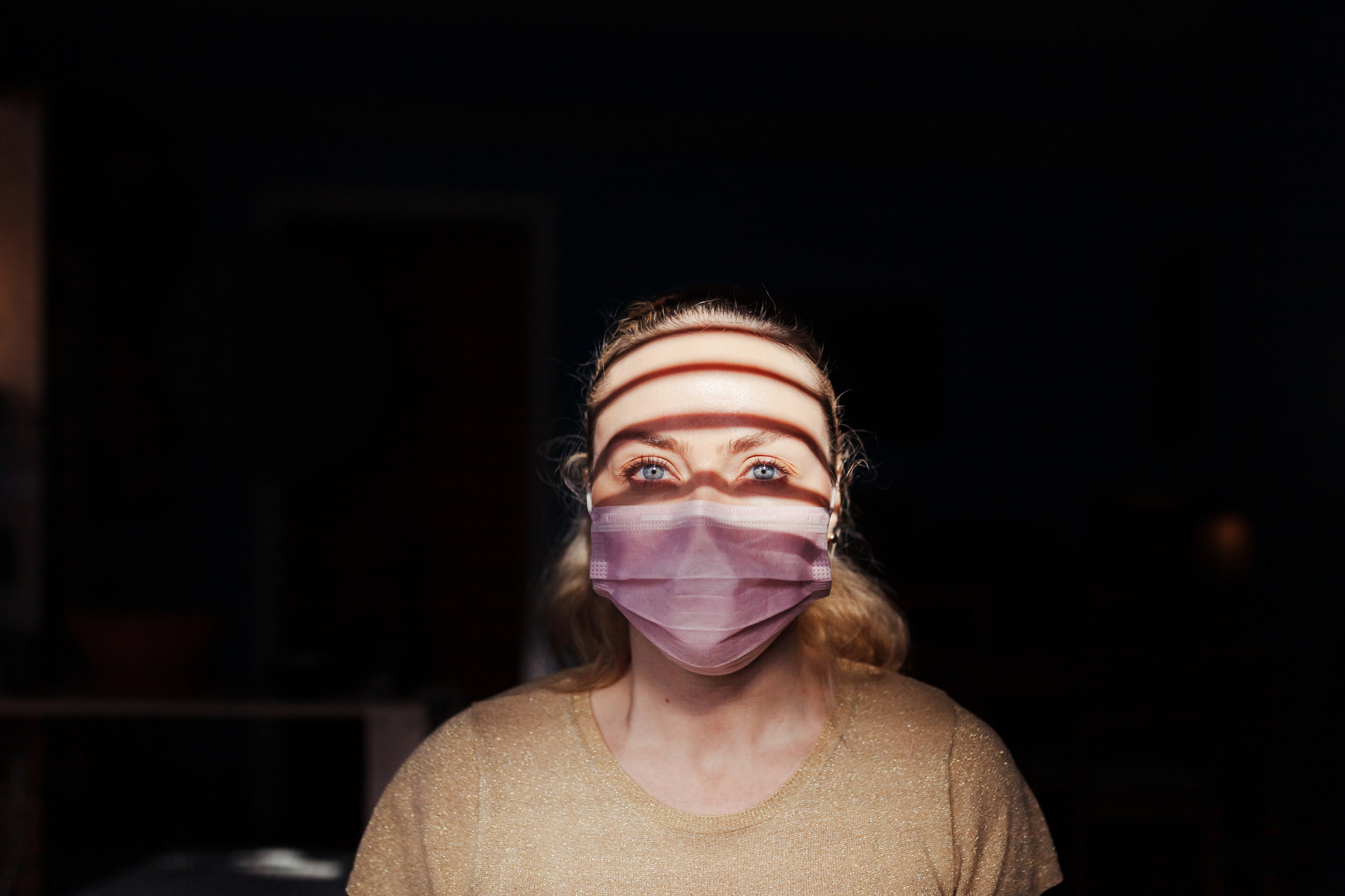 Woman wearing a surgical mask during quarantine in her house. Image credit: Manu Reyes, iStock