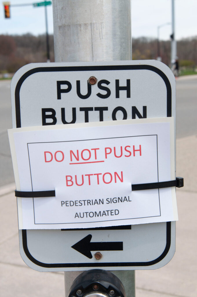 A sign in downtown Ann Arbor warns pedestrians to not push the button. (Photo by Henry Hedly, Michigan Medicine)