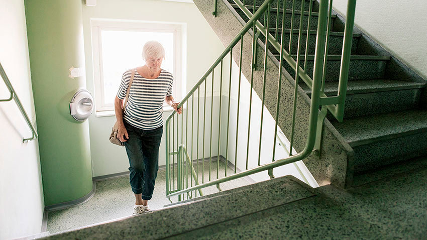 An older woman ascending a staircase. Image credit: Getty Images.