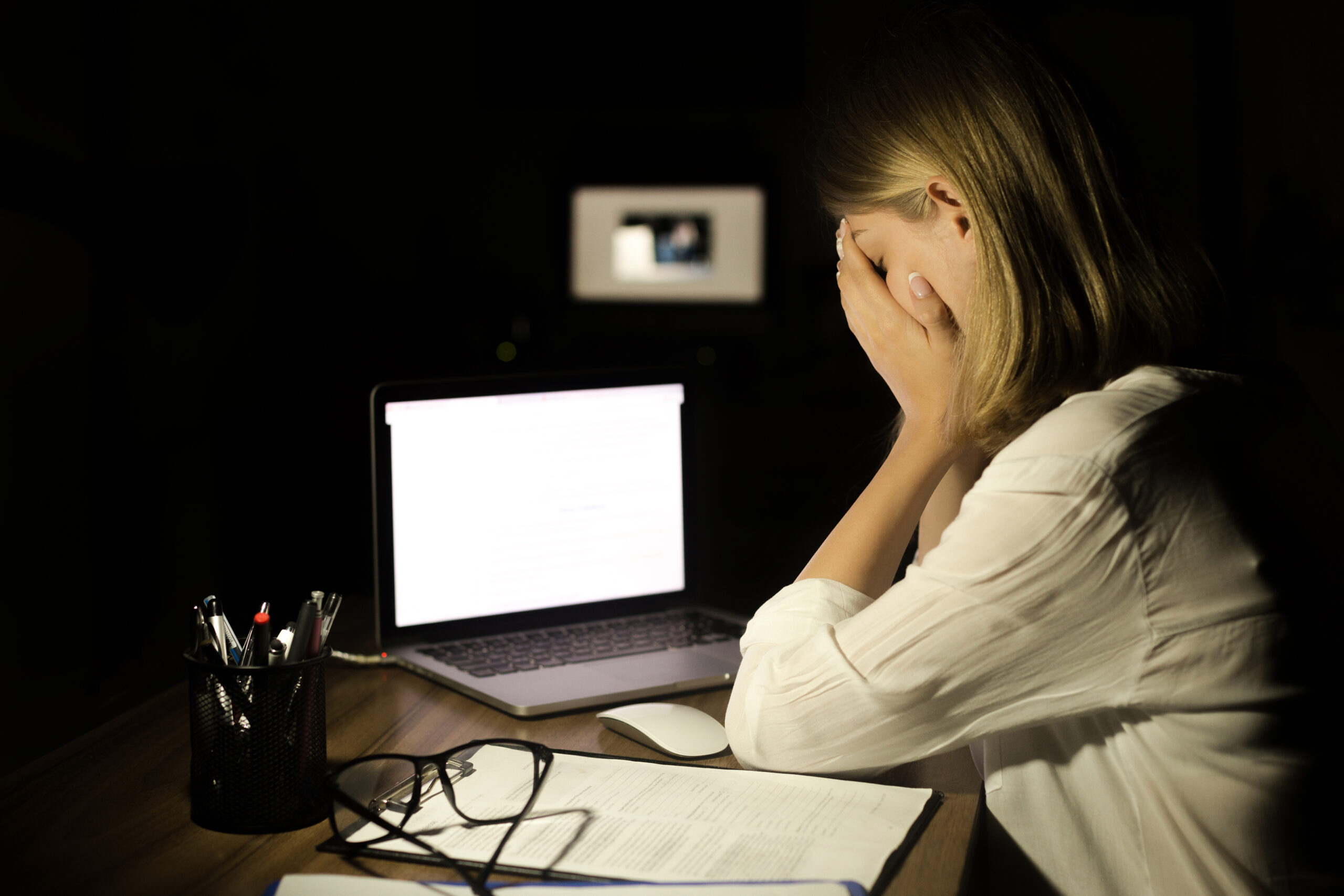 Scared and stressed woman with laptop computer and mobile phone suffering cyber bullying and online harassment. Image credit: iStock.
