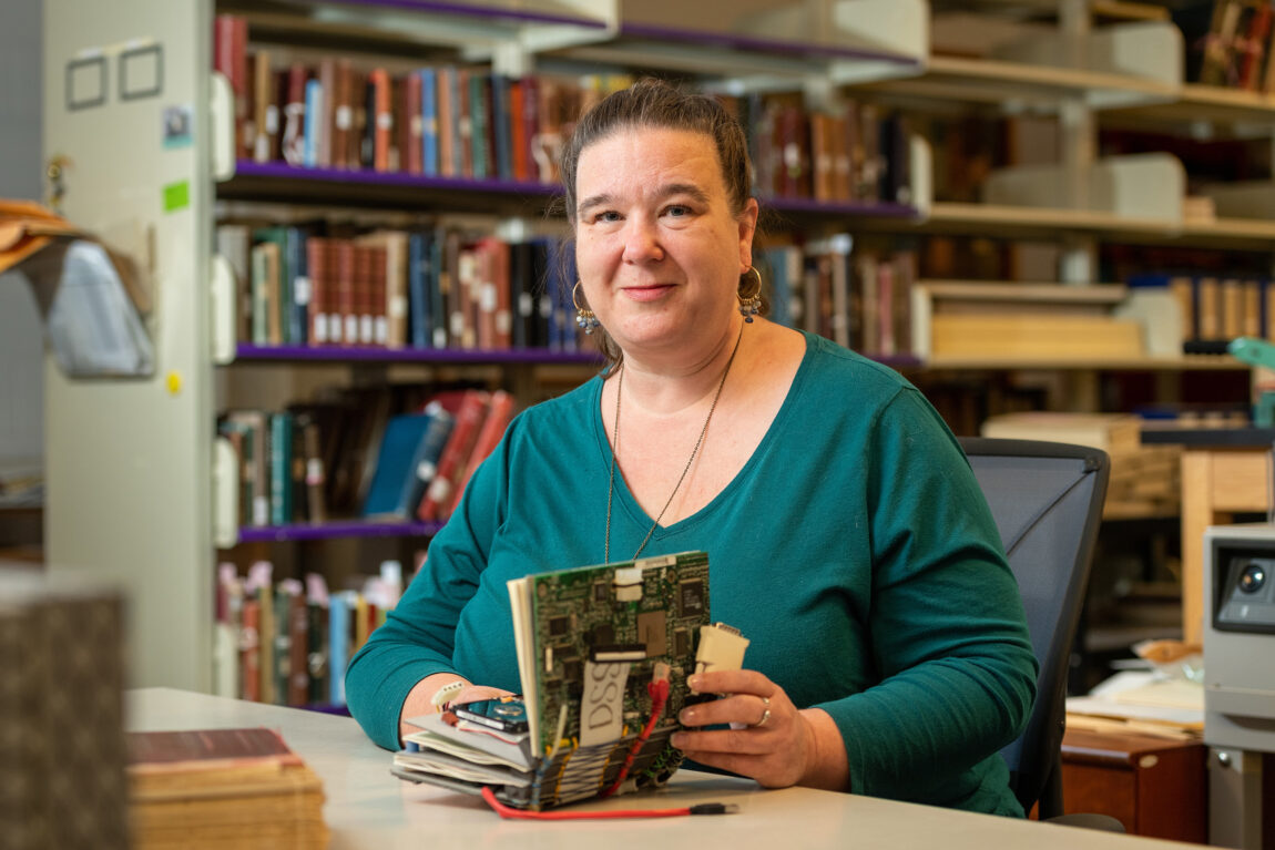Lara Unger, digital conversion supervisor at the U-M Library, sits in the Buhr Building where she works and holds “Ebook,” an artist’s book she created for a longtime desktop support services leader who retired. (Scott C. Soderberg, Michigan Photography)