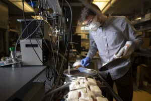 Andrew Gayle, mechanical engineering PhD candidate, places a solar-transparent aerogel into a device that will apply an atom-thick coating for use in solar-thermal power plants. Image credit: Evan Dougherty/Michigan Engineering