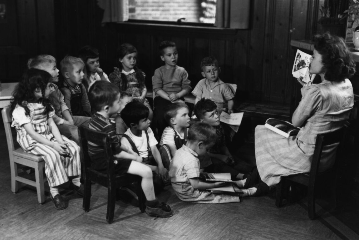 Students look on as their teacher reads a book aloud in a class that was taught in a university-operated elementary school. 