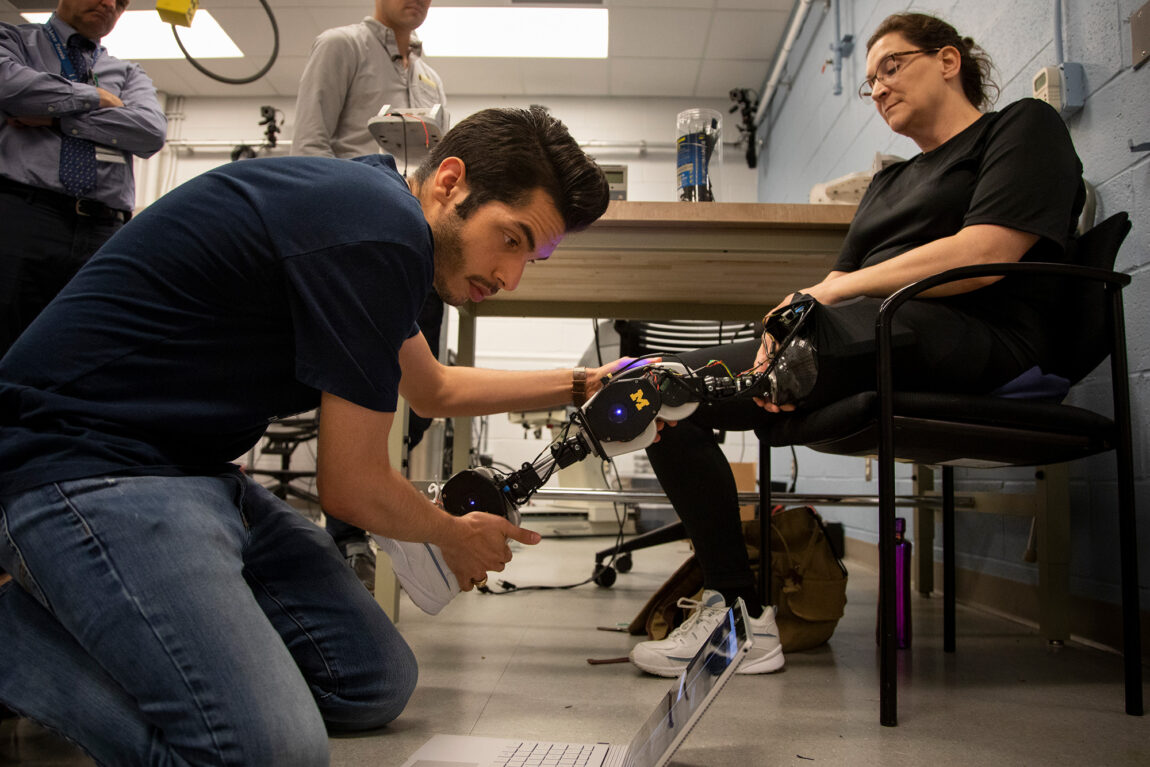 Alejandro Azocar (left), a mechanical engineering graduate student research sssistant, helps Dawn Jordan Musil test an open-source robotic leg.