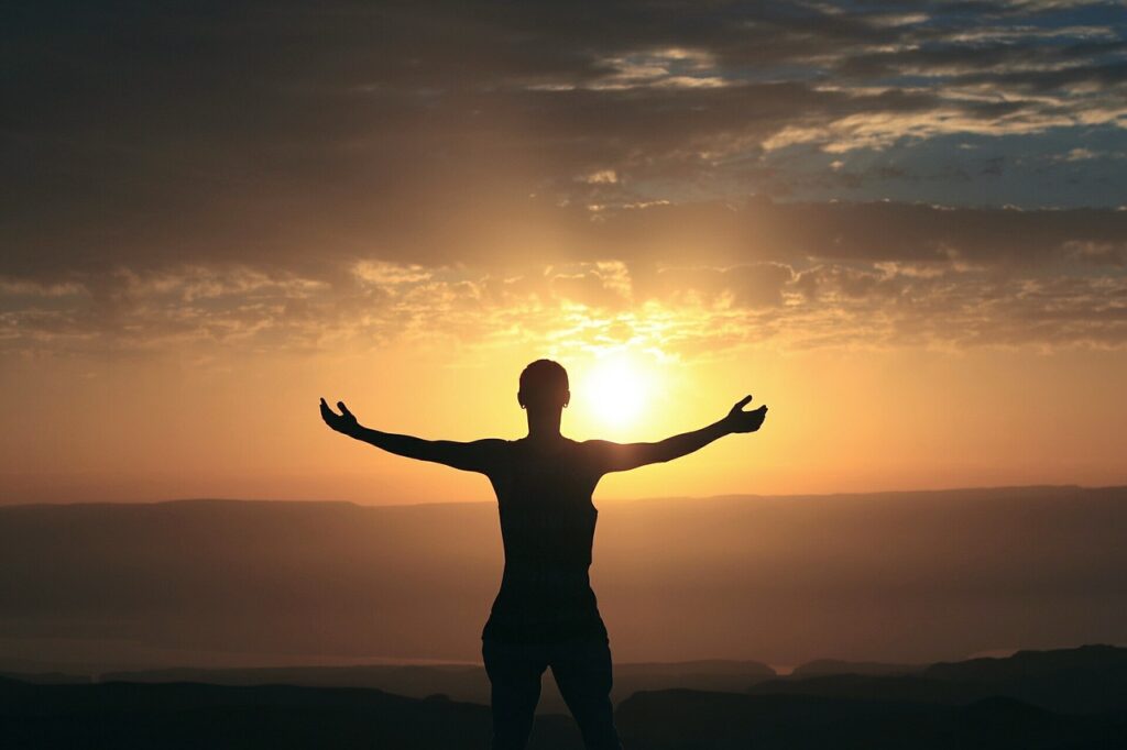 Silhouette of a person with arms outstretched at sunrise. Image credit: avi_acl, Pixabay.com